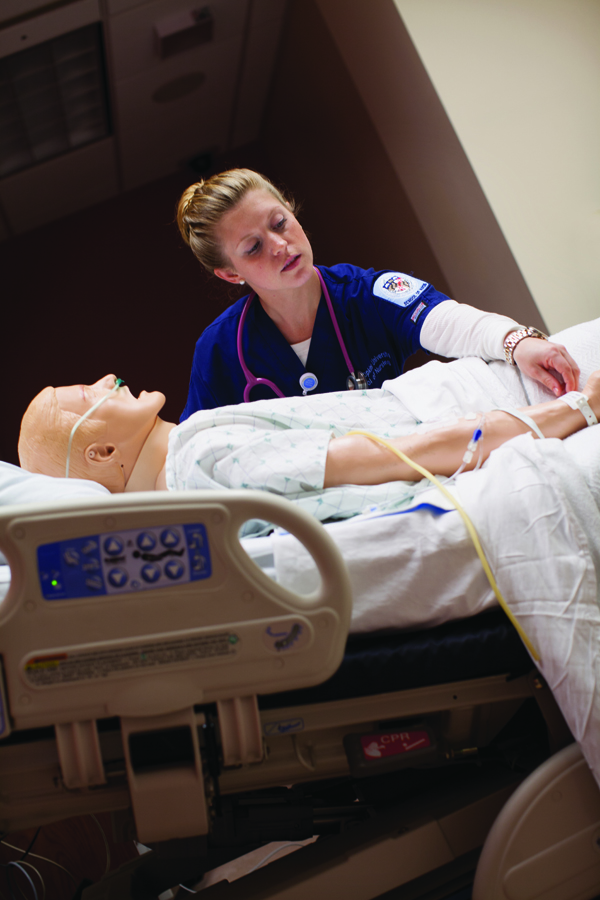 Simulating the everyday: Nursing student Sarah Krieg tends to a manikin in a simulation room in the Pinkard Building. Increasingly, nursing students practice diagnostic and treatment skills on such high-fidelity simulators--manikins with beating hearts that breathe, talk, bleed, vomit, urinate, seize, shake, and have babies. An instructor sets the scenario from a control room. Photograph by Chris Hartlove (www.chrishartlove.com)